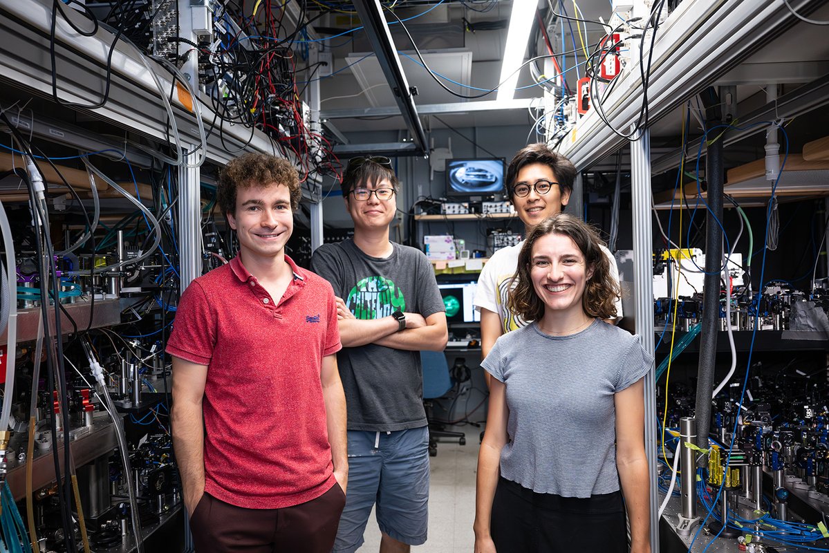 Researchers stand between to optical benches used for quantum experiments.