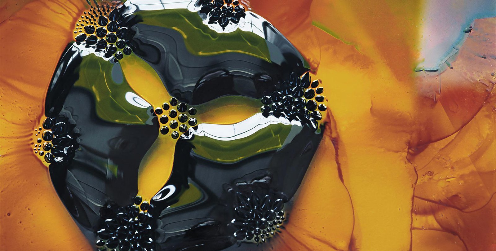 photo of a 2-cm drop of ferrofluid, placed on a glass slide, under which are seven circular magnets.
