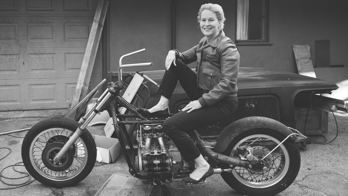 Black-and-white photo of Frances Arnold wearing a leather jacket and high heels while sitting on a motorcycle