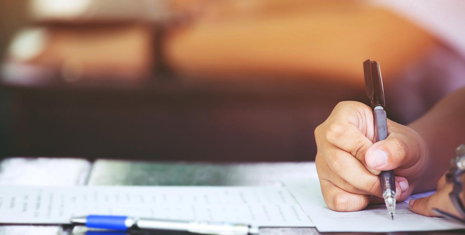 Stock photo of a person's hand writing on a paper at a desk
