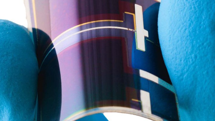 fingers hold a small flexible solar cell