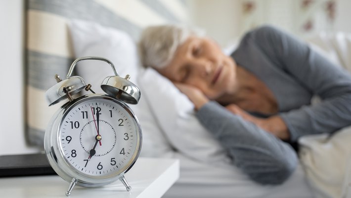 Stock image of a person sleeping next to an alarm clock