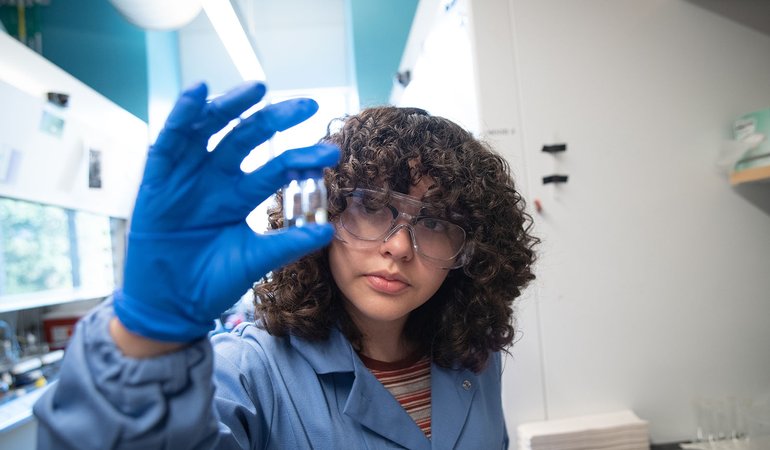 Wendy Granados Razo examines two test tubes with fluid in them