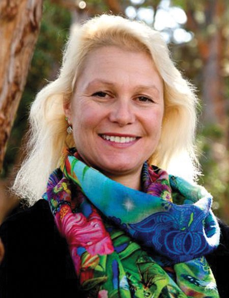A portrait of Julia Greer smiling and wearing a colorful scarf.