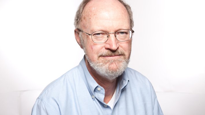A portrait of Robert Grubbs. He wears a button-up shirt and glasses and looks at the camera.