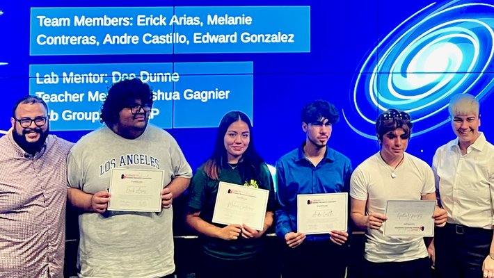 Six people stand smiling in front of a screen that says "Lyman Alpha Emiting Galaxies Analysis"