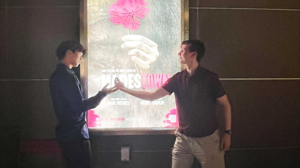 Students pose in front of a playbill poster for Hadestown