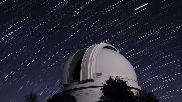 The white dome of the Hale Telescope with stars streaking by overhead.