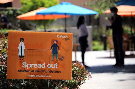 A sign cautioning people to stay six feet distant from each other alongside a path