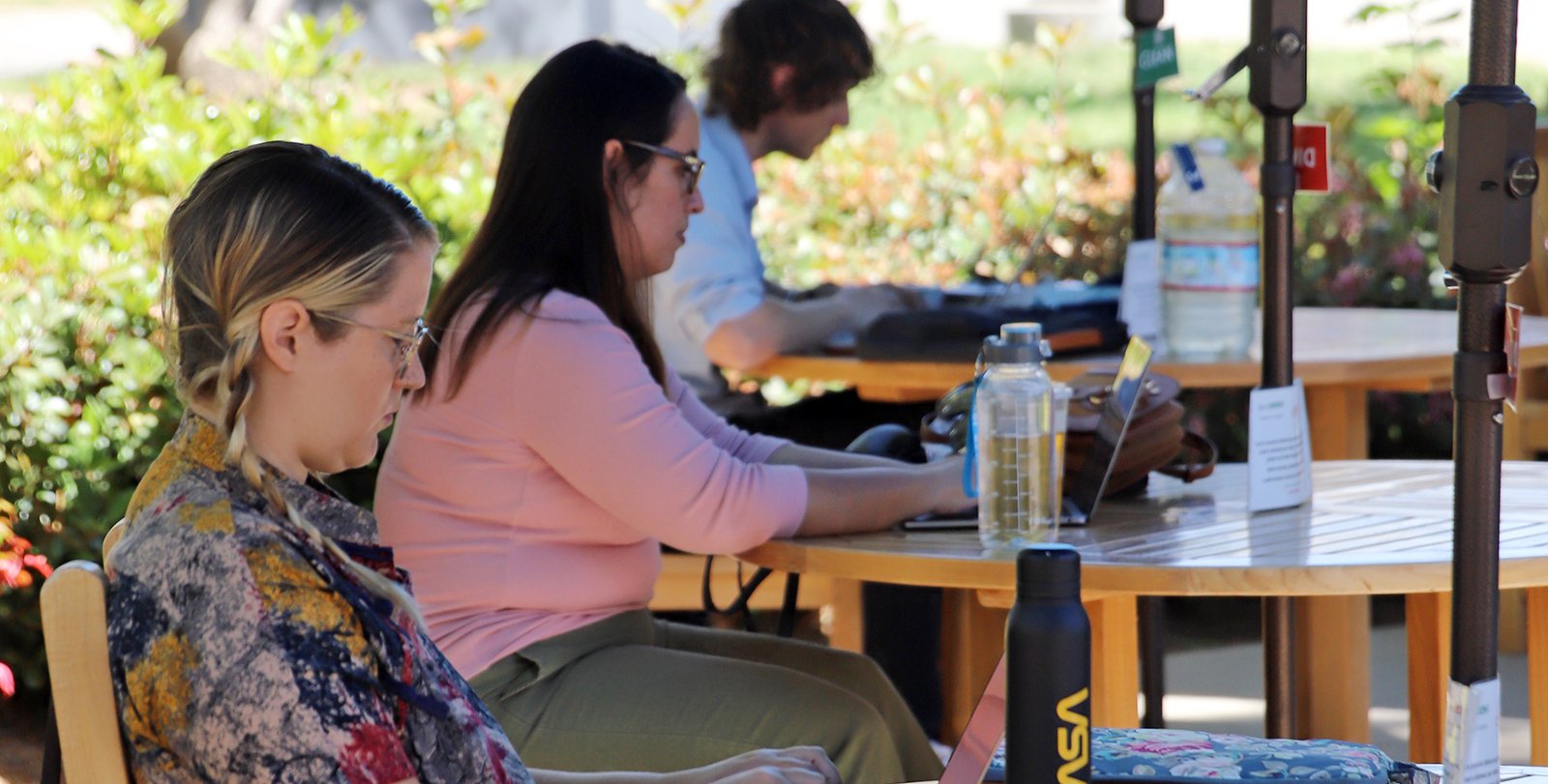 Patrons work on laptops under umbrellas by the Red Door Cafe
