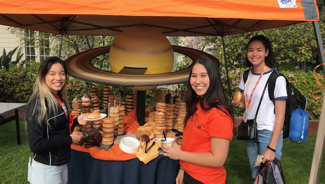 Students next to a table of donuts arranged like the planet saturn.
