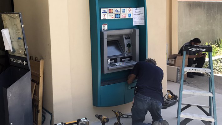 A workman helps finish the installation of an ATM on the west side of Chandler.
