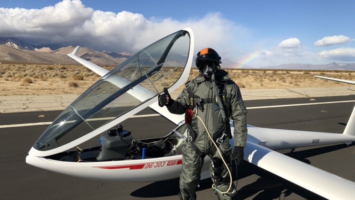 Keith Schwab in flight suit next to glider on desert runway