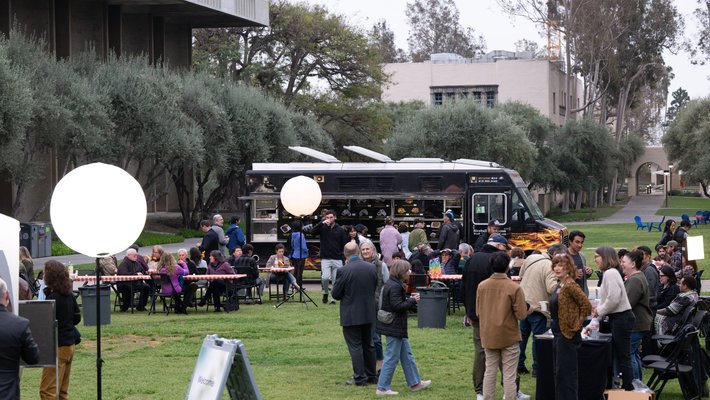 Image of Beckman mall with several people mingling near tables and a food truck
