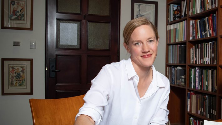Portrait of new dean of Jennifer Jahner wearing a white shirt in front of a bookshelf