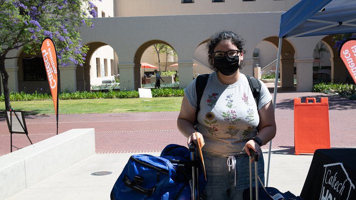 Student Jennifer Rodriguez stands with her luggage in front of the Moore Laboratory of Engineering