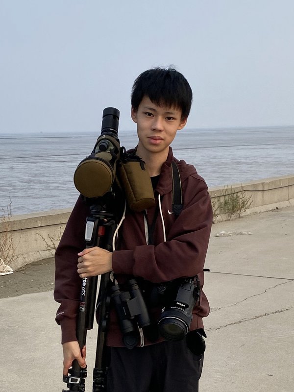Jonathan Hu holding a tripod and camera gear