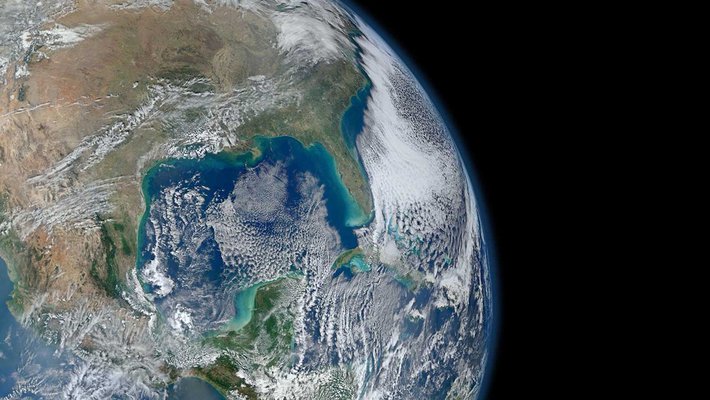 An image of Earth from orbit. Blue ocean and swirling white clouds are seen.