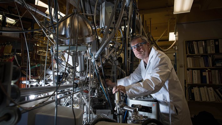 Konstantinos Giapis stands in front of his oxygen reactor. It appears as a complex tangle of tubes and wires.