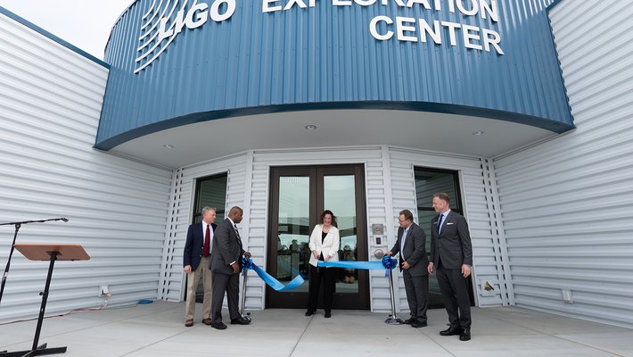 Picture of Amber trunk cutting the blue ribbon in front of the LIGO Exploration Center.