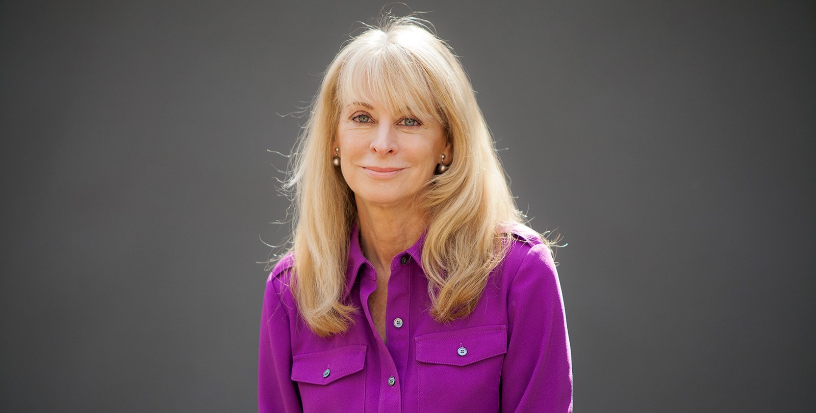 Portrait of Jenijoy La Belle. She has blond hair and is wearing a purple shirt.