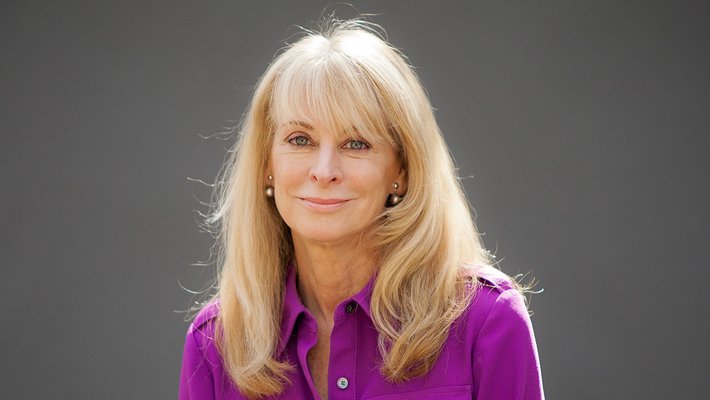 Portrait of Jenijoy La Belle. She has blond hair and is wearing a purple shirt.