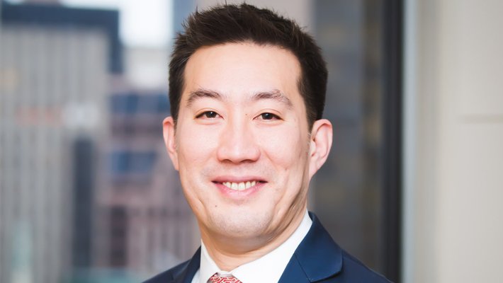 portrait photo of Ken Lee wearing a dark suit and red tie
