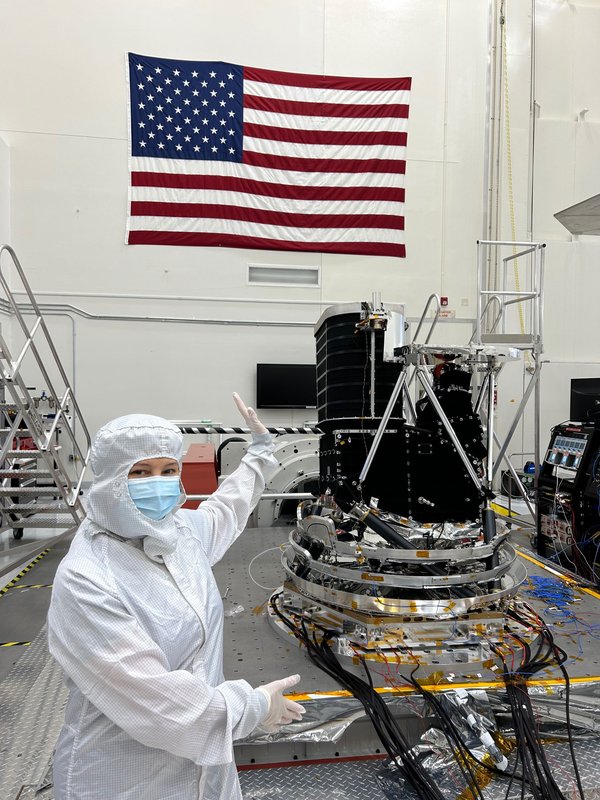 JPL Director Laurie Leshin poses with SPHEREx at JPL.  The instrument is mounted to a vibration table for simulating shaking during launch.