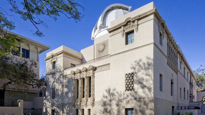 A cream-colored, three-story building with ornate sculptures