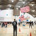 students stand around a gym with white and pink blimps flying above