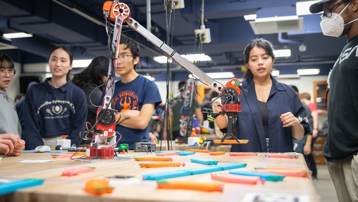 A robotic arm lifting a piece of toy train track.