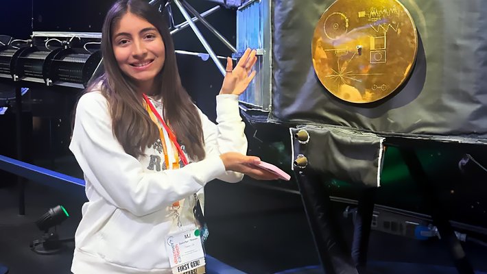 Maria Jose "MJ" Sanchez Rincon at JPL alongside a model of the Voyager 1 spacecraft