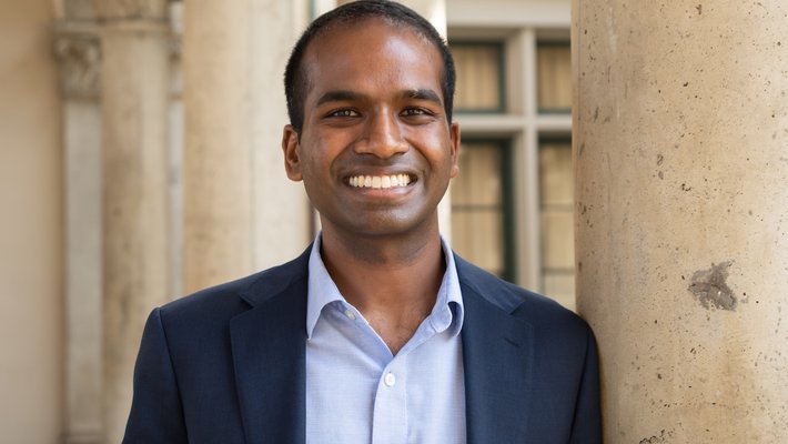 Professor Karthish Manthiram stands in front of columns on campus