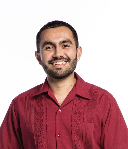A man in a red button up shirt smiles for a photo