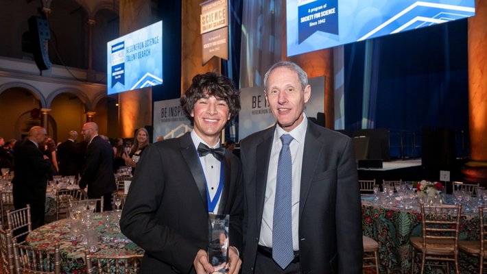 Regeneron Science Talent Search winner Matteo Paz and Caltech president Thomas Rosenbaum stand smiling together at a formal event