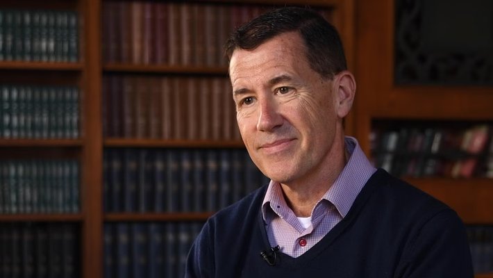 R. Michael Alvarez, Flintridge Foundation Professor of Political and Computational Social Science, seated in a library, surrounded by shelves filled with books.