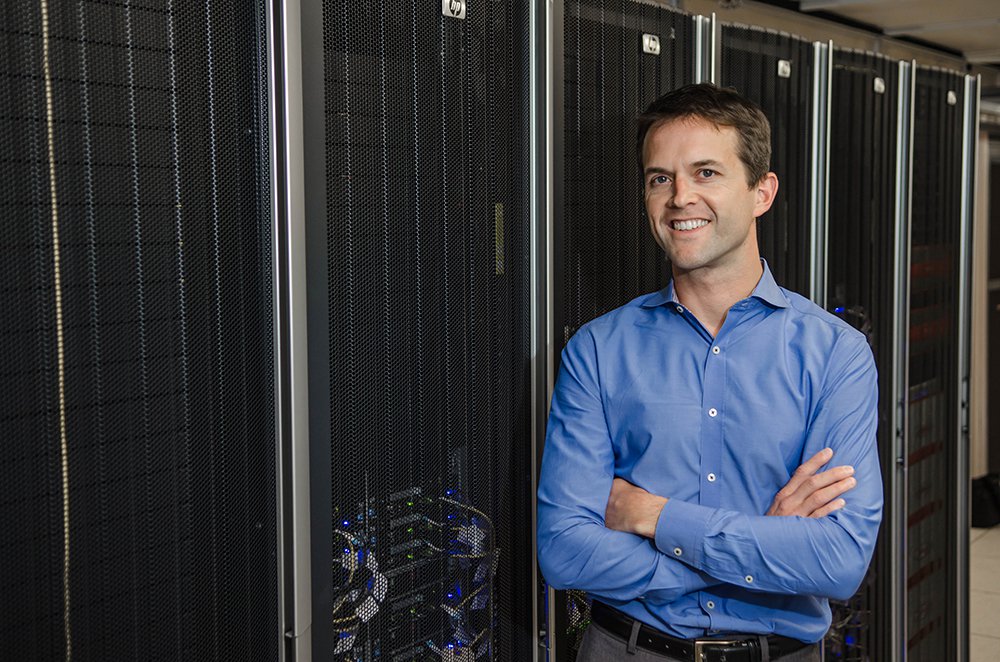 Tom Miller, professor of chemistry, stands in front of a rack of computers.