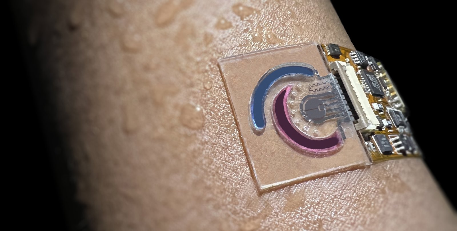 A human arm covered with droplets of water has a small sensor attached to it. The sensor is a clear membrane with sectors and wires.