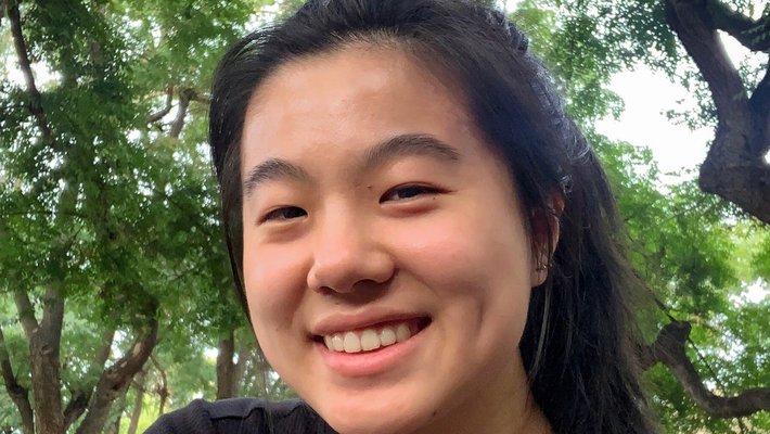 Jiang smiling at the camera, outdoors in a black t-shirt