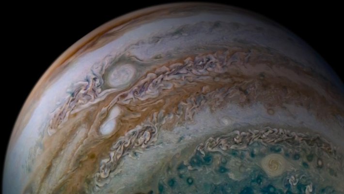 Two white oval storms merge in an orange band on Jupiter