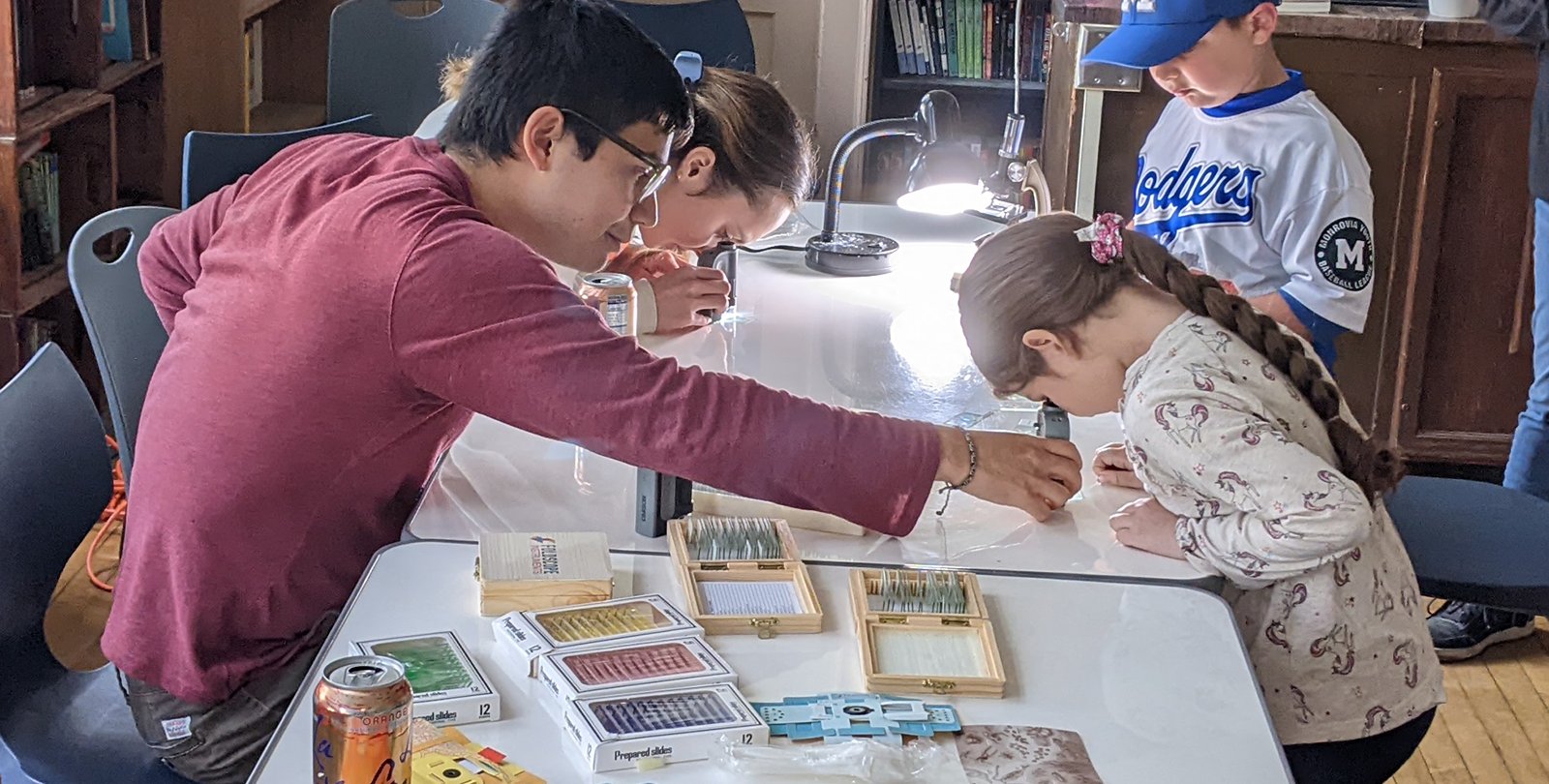 An adult helps a child use a microscope