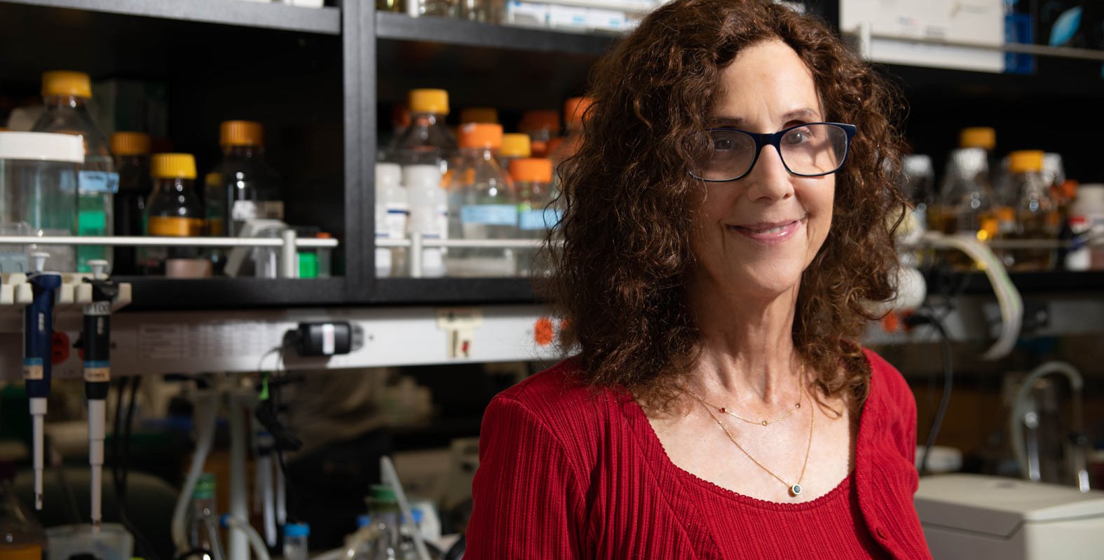 Portrait of Professor Pamela Bjorkman in her biology lab with flasks and pipettes behind her