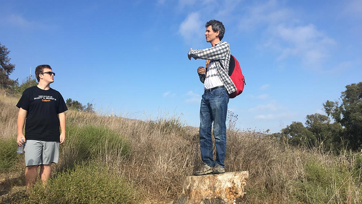 Paul Asimow, the Eleanor and John R. McMillan Professor of Geology and Geochemistry, talks to students from atop a stump during the Frosh Camp geology hike.