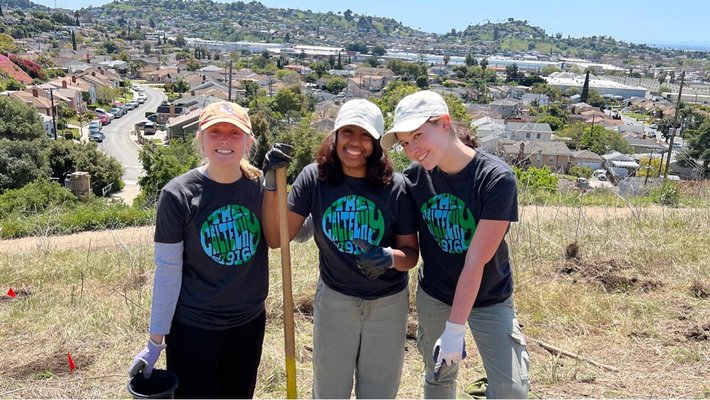 Three participants in the 2024 Caltech Y Make a Difference Day rest and smile for the camera after planting trees.