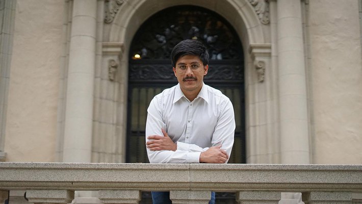 A man with dark hair, glasses, mustache, and white shirt.