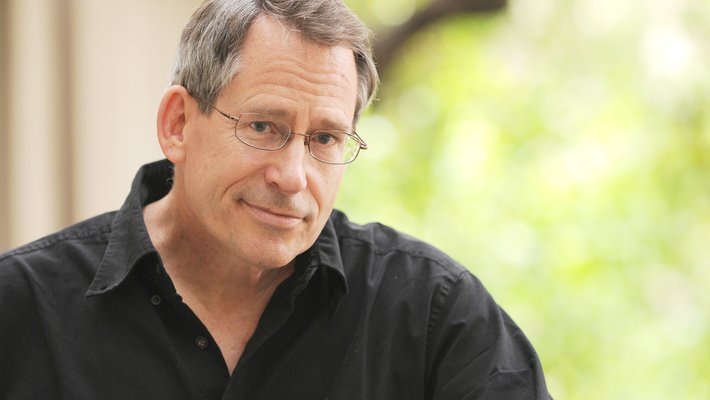 Professor John Preskill, a middle-aged white man, wears wire-rimmed glasses and a black shirt.