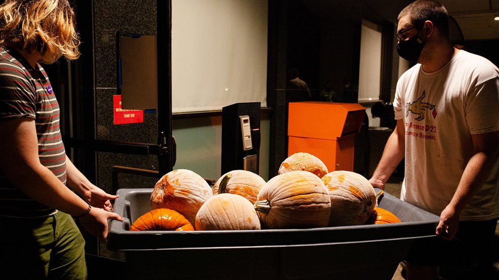 Two men haul a container of frozen pumpkins