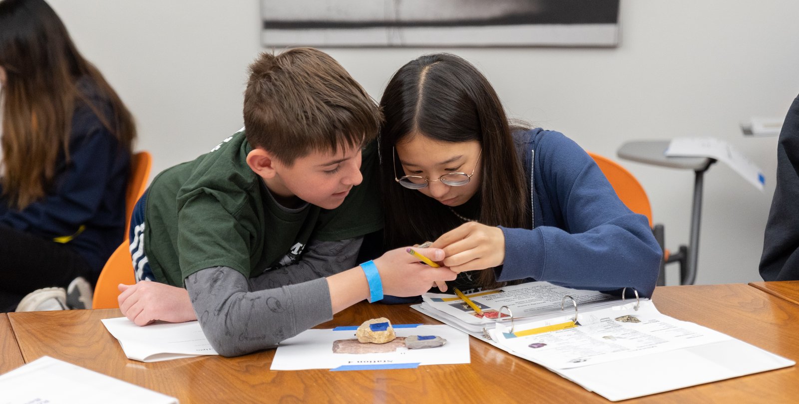 Two young students look at a rock sample together.