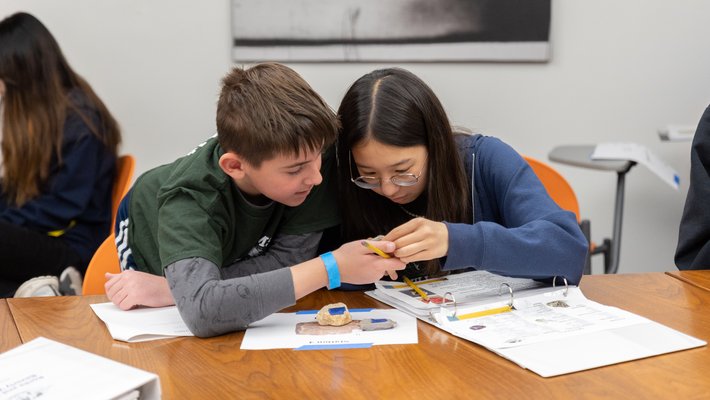 Two young students look at a rock sample together.