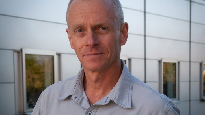 A portrait of Ralph Adolphs. He wears a light blue collard shirt.